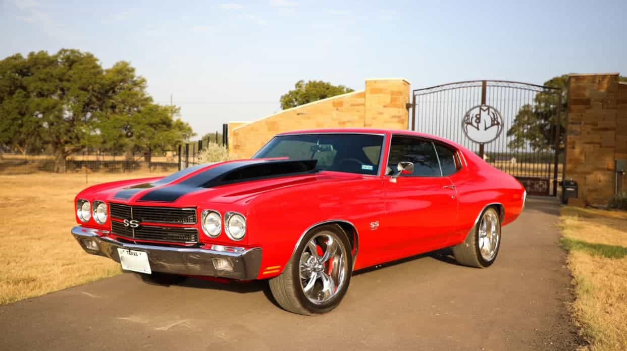 A red 1970 Chevrolet Chevelle muscle car with black racing stripes and a shiny finish.