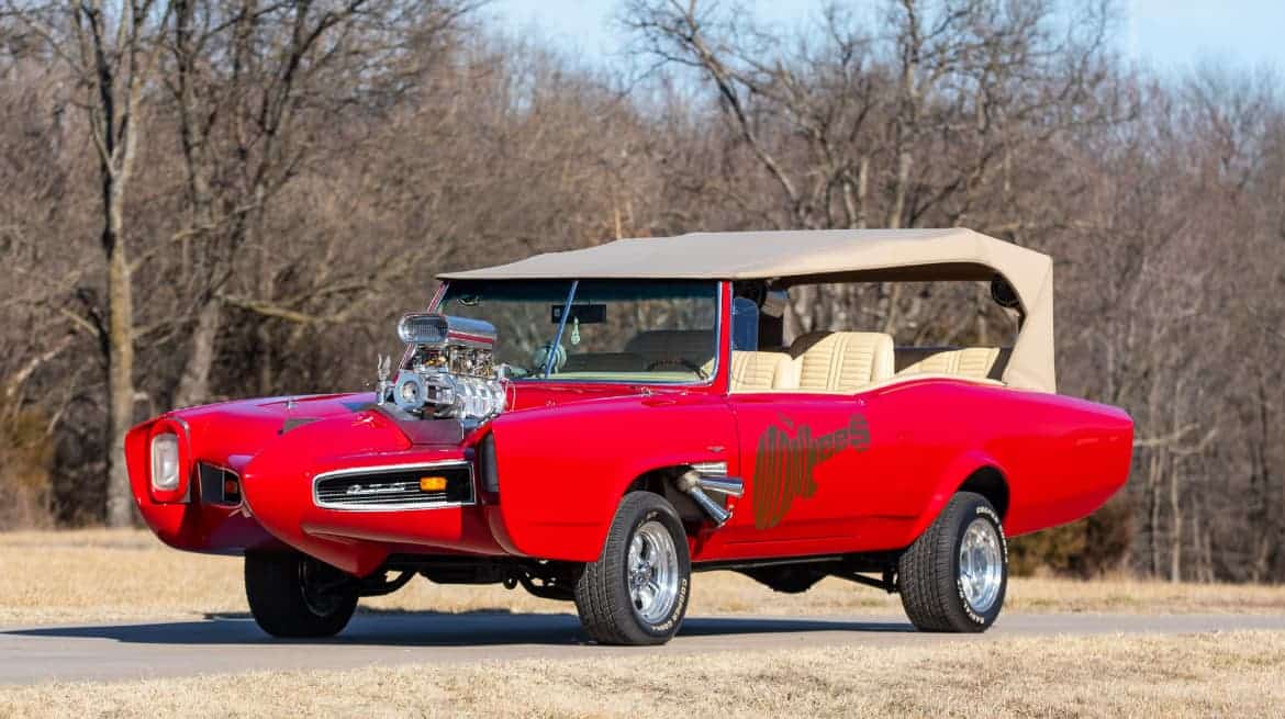1967 Pontiac Monkeemobile Replica: A red muscle car with a beige interior and the Monkees livery, featuring autographs of Mickey Dolenz and Peter Tork on the dashboard.